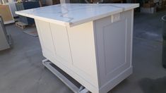 a white kitchen island sitting in the middle of a room with lots of cabinets on it