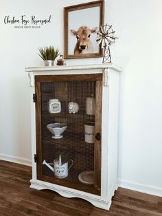 a white cabinet with glass doors and a cow's head on the top shelf