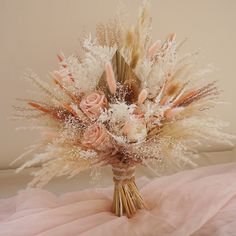 a bouquet of dried flowers and feathers on a bed