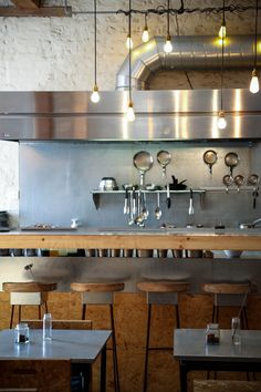 an industrial style kitchen with stainless steel appliances and wooden stools in front of the counter