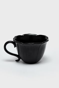 a black cup sitting on top of a white table