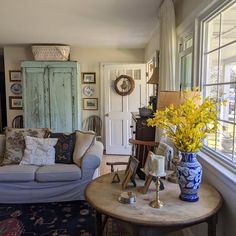 a living room filled with furniture and flowers in vases on top of a table