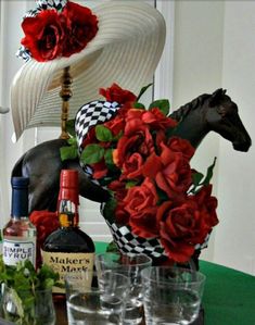 a table topped with bottles and glasses filled with flowers next to a horse statue on top of a wooden table