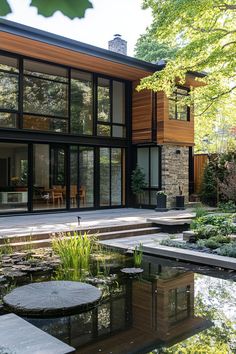 a modern house with large windows and lots of plants in the front yard, surrounded by water