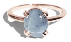 a rose gold ring with an oval blue topazte stone on the front and side