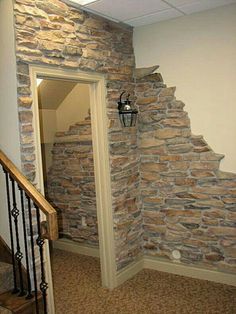 an open door leading to a room with stone walls and stairs in the corner, next to a light fixture