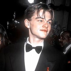 a young man in a tuxedo and bow tie at an awards event with other people around him