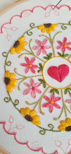 a close up of a embroidery on a piece of cloth with flowers and a heart