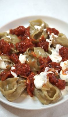 a white plate topped with dumplings covered in sauce