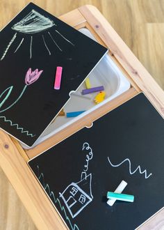 two children's chalkboards with crayons on them sitting on top of a wooden table