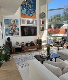 a living room filled with lots of furniture and pictures on the wall above it's windows