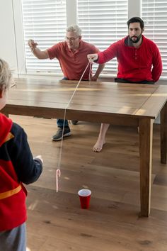 two adults and a child playing with toys on the floor in front of a table