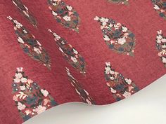 a close up of a red fabric with flowers and leaves on it, as well as a white background