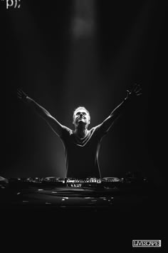 a man that is standing in the dark with his arms up and headphones on