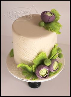 a white cake with purple flowers and green leaves