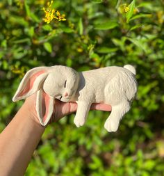 a hand holding a small white rabbit figurine