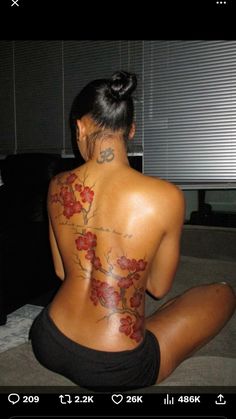 a woman sitting on the floor with her back to the camera and tattoos on her body