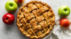 an apple pie on a table with apples around it