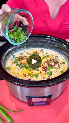 a woman is pouring something into a crock pot filled with soup and vegetables on the side