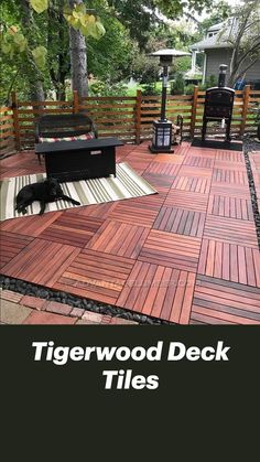 a black dog laying on top of a wooden deck next to a bbq grill