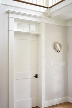 an image of a white door in a room with wood floors and light fixture on the wall