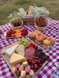 an assortment of cheeses, crackers and fruits on a picnic table