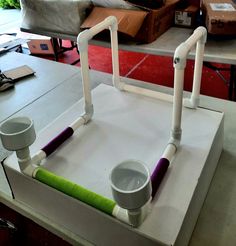 a white table with two cups on it and some pipes attached to the back of it