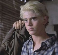 a young man with blonde hair wearing a plaid shirt and looking off to the side