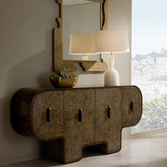 a large mirror sitting on top of a wall next to a wooden cabinet with two lamps