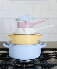 four pots stacked on top of each other in front of a gas stove with white tiles