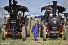 two men standing next to an old fashioned steam engine at a car and tractor show