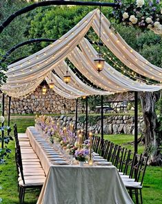 an outdoor dining area with tables and chairs covered in white drapes, lit by lanterns