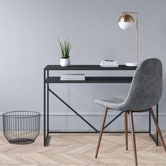 a desk with a chair, lamp and potted plant on it in front of a gray wall