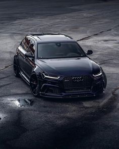 the front end of a black audi suv parked in a parking lot with it's door open