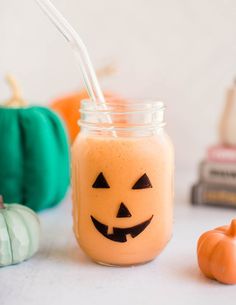 a glass jar with a straw in it and two pumpkins on the table next to it