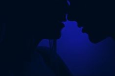 two people are kissing in the dark with blue light behind them and one person has their head turned to the side