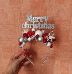 a person is holding up a christmas headband with ornaments and snowflakes on it