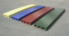 four different colors of corrugated roofing laying on the ground in an empty parking lot