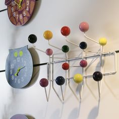 an owl clock is hanging on the wall next to some colorful balls and pins that are attached to it