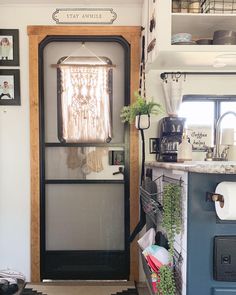 an open door leading to a kitchen with plants on the counter and pictures above it