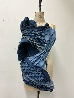 a mannequin is covered in blue fabric on a white surface with a black top