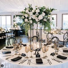 a table set with white flowers and place settings for an elegant dinner or reception party