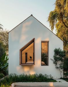 a white house with two windows and plants