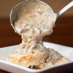 a spoon scooping some food out of a white square dish on a wooden table