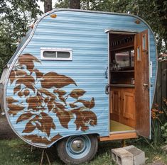 an old trailer converted into a kitchenette with flowers painted on the side and door