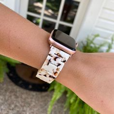 an apple watch on someone's arm wearing a white and brown bracelet with small squares