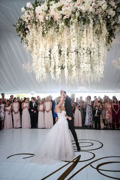 a bride and groom share their first dance in front of the crowd at their wedding reception