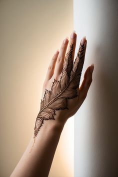 a woman's hand with a hendi that has a leaf on it and is next to a wall