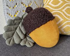 three pillows with different colors and designs on top of each other, one has an acorn