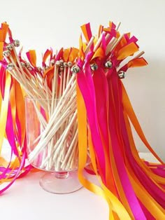 a vase filled with lots of colorful streamers on top of a white table next to a wall